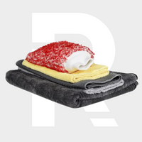 The Accessoire Package features a stack of three folded towels in dark gray, yellow, and light gray with a red and white textured cloth, ideal as a 600 GSM Drying Towel or for pairing with your favorite auto accessories, set on a light gray background.