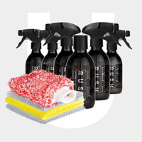 The Try Out Package features six black RUSH spray bottles for interior and wheel cleaning, displayed behind four stacked cleaning cloths in white, yellow, gray, and red-and-white on a light gray background.