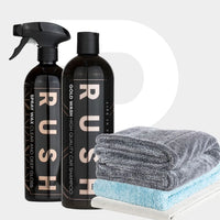 The Showroom Finish Package features two black “RUSH” bottles—Spray Wax and Gold Wash—beside gray, white, and light blue towels, including a premium droogdoek, all arranged against a light gray background with a large white P.