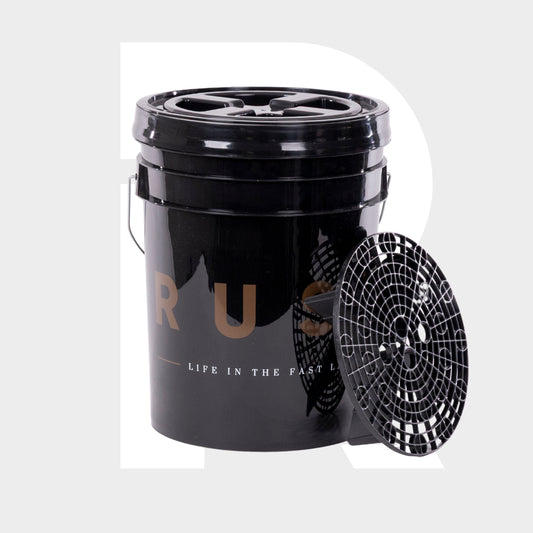 A black Detailing Bucket 20L with a handle and Grit Guard sits beside it. "LIFE IN THE FAST LANE" in white and gold decorates the bucket. Perfect for the 2-bucket method, the setup is photographed on a light gray background.