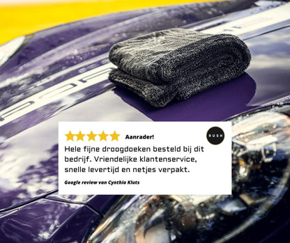 A soft, folded Master Drying Towel 1200 GSM rests on the shiny hood of a purple car. Below, a 5-star Dutch review praises this droogdoek auto and the company's outstanding customer service.