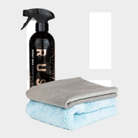 A 1+1 GRATIS Spray Wax Package sits with a gray microfiber cloth and blue plush towel on a plain background—your essentials for een beschermende waxlaag en ultieme auto glans.