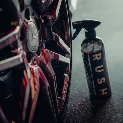 A close-up of a car wheel with a spray bottle labeled Iron Remover, the perfect velgenreiniger for removing vliegroest, placed upright next to the tire on a dark surface.