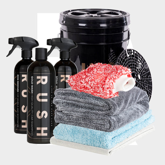The Bonus Bucket Kit includes three black spray bottles, a black bucket with grit guard, a red-and-white wash mitt, stacked microfiber towels (gray, blue, white), and RUSH Gold Wash for exceptional car cleaning results.