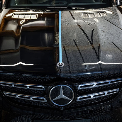 A black Mercedes-Benz hood split by blue tape shows the impact of Ceramic Sealant: the left side is clean and polished, while the right stays dirty and water-spotted, clearly demonstrating the power of this keramische lakbescherming.