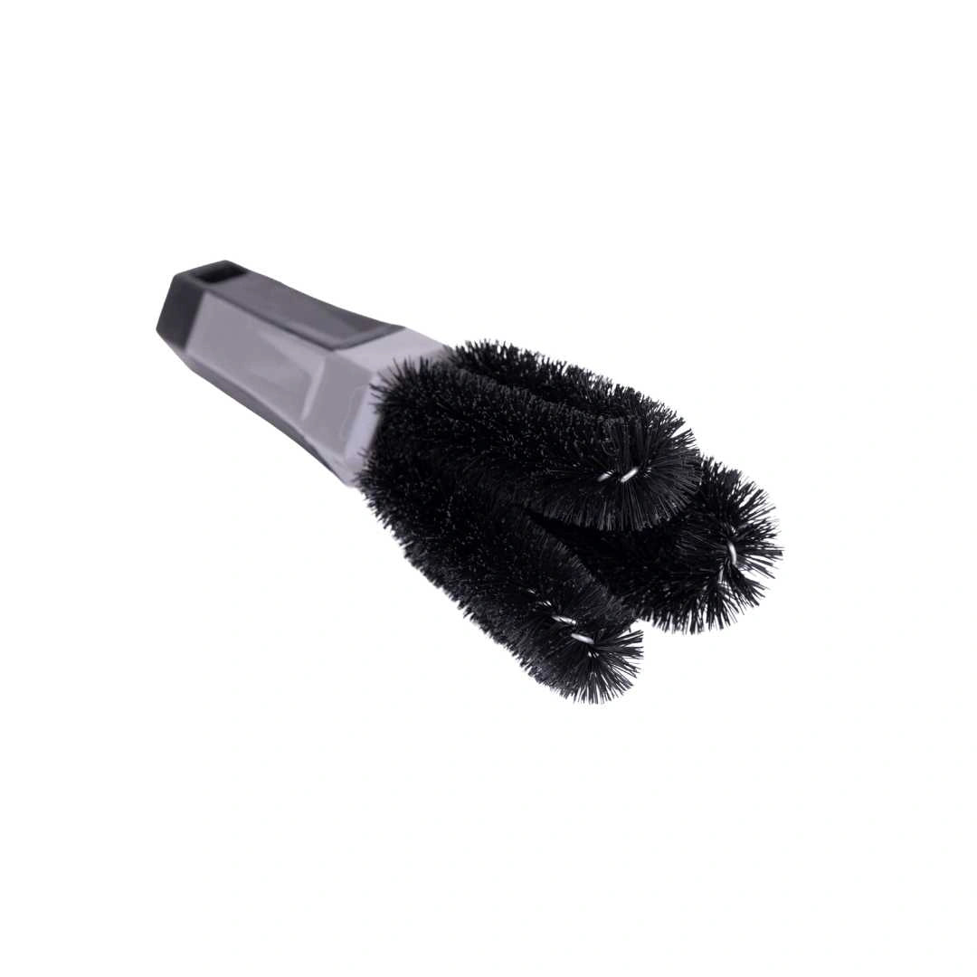 The Three Prong Brush, featuring black and gray design with three cylindrical bristled heads and a plastic handle, is ideal for cleaning bike drives or chains in tight spaces, shown isolated on a white background.