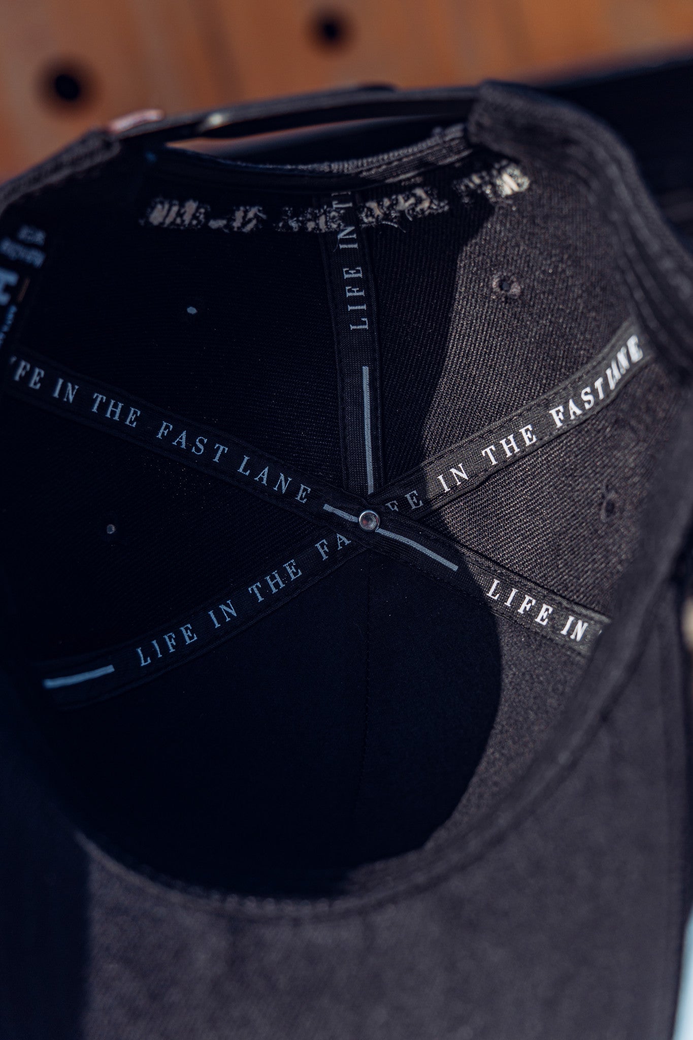 Close-up of the inside of the RUSH Baseball Cap, showing "LIFE IN THE FAST LANE" printed along the inner seams of this adjustable cap.