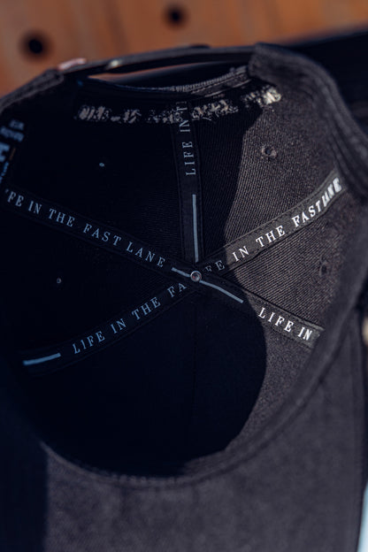 Close-up of the inside of the RUSH Baseball Cap, showing "LIFE IN THE FAST LANE" printed along the inner seams of this adjustable cap.